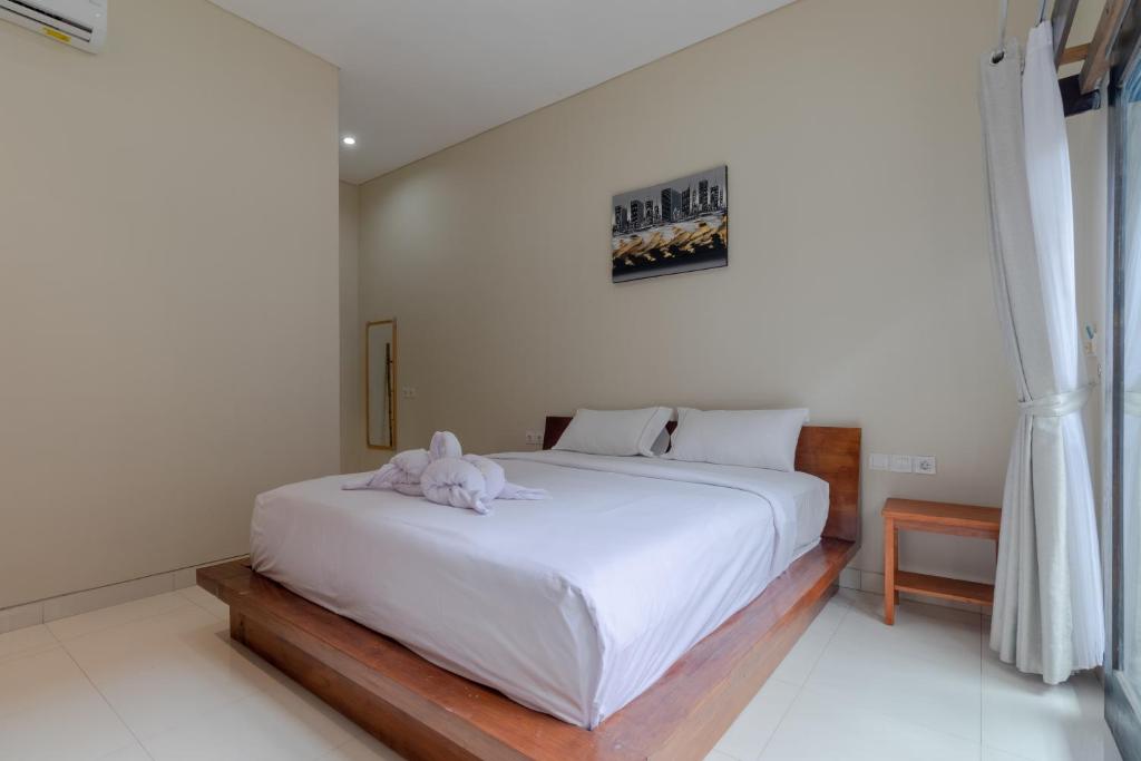 新加拉惹Josh Guest House的卧室配有一张白色的床,上面有一只动物填充物