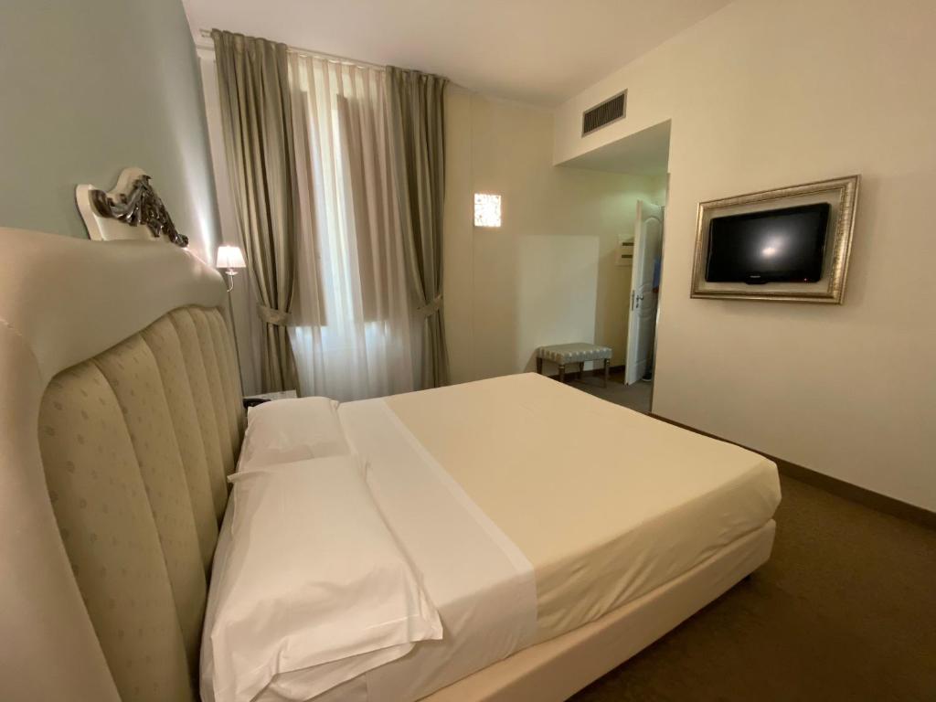 巴里JR Hotels Oriente Bari的酒店客房设有白色的床和电视。