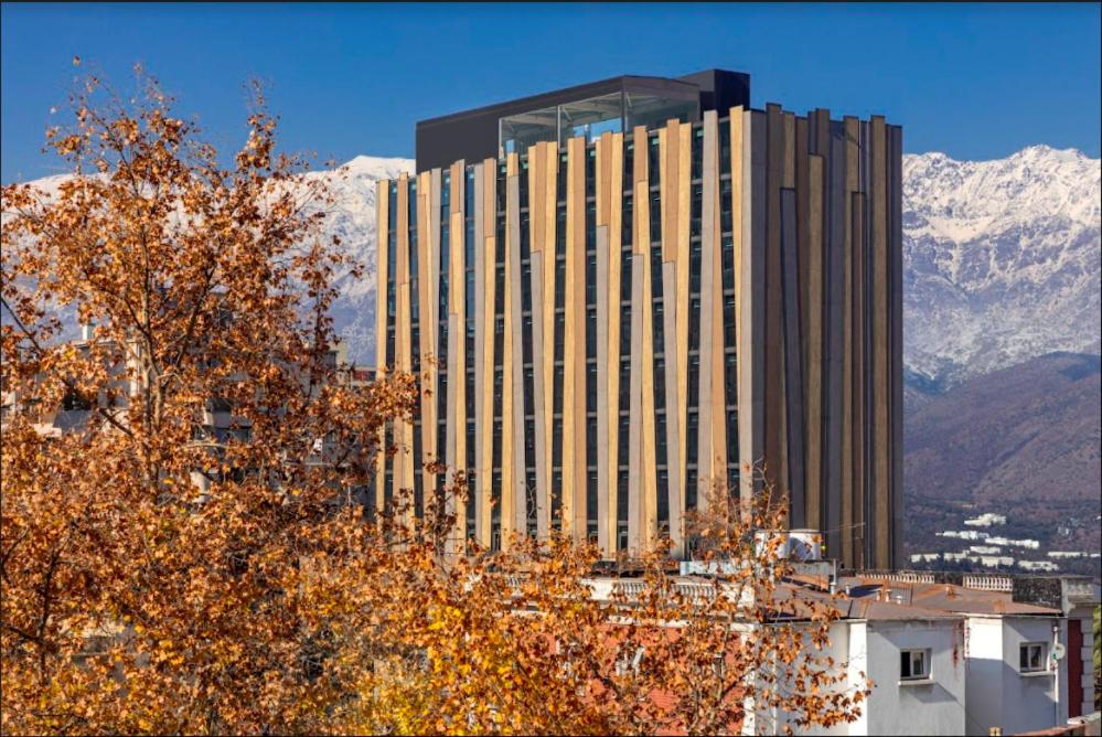 圣地亚哥Hotel Nodo - Primer hotel explorador urbano的一座高大的办公室大楼,后面是群山