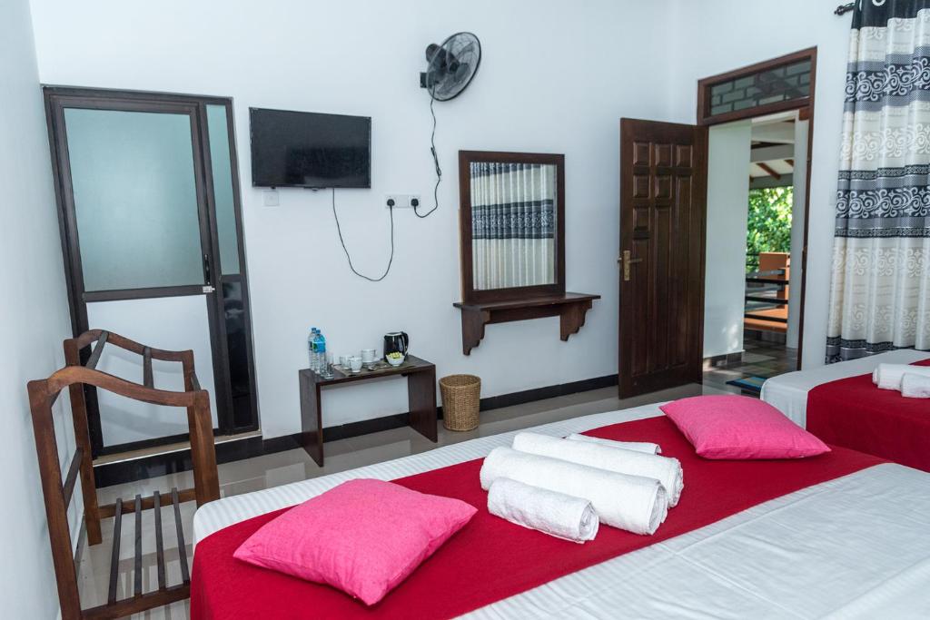 丹不拉Sadee's Place的一间卧室配有两张带红色床单和粉红色枕头的床。