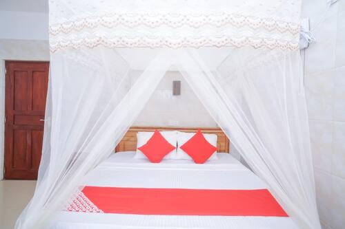 希克杜沃Hotel Cranberry的白色的天蓬床和红色枕头