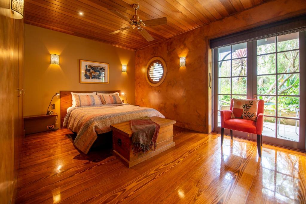 RhyllRhyll Haven Luxury Getaway Apartments的一间卧室配有一张床和一张红色椅子