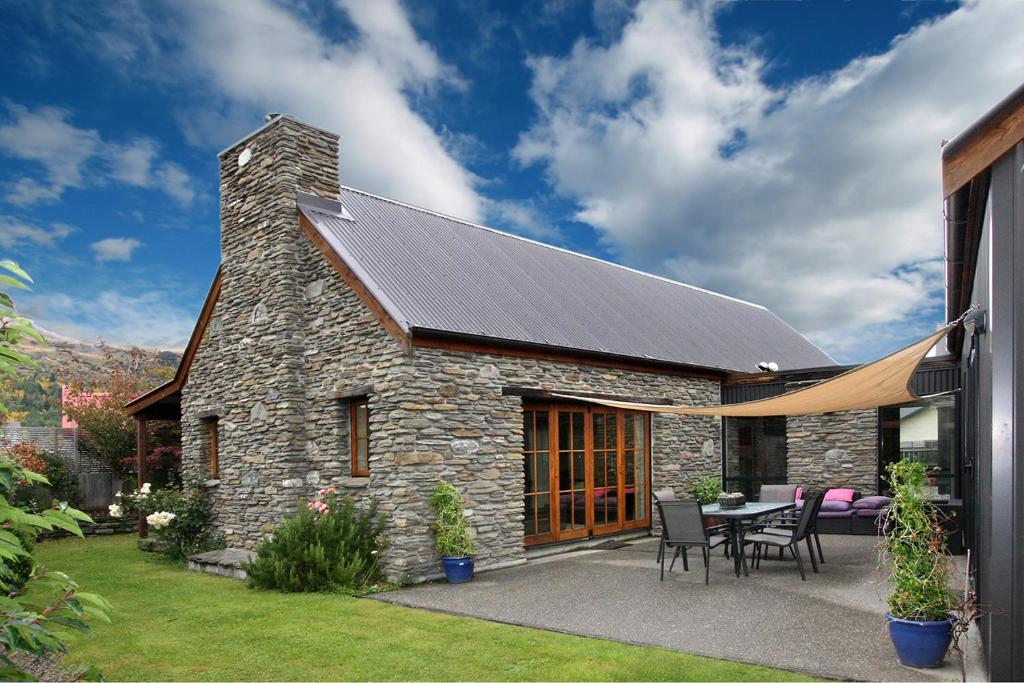 箭镇Maytime Cottage - Arrowtown Holiday Home的一座带太阳能屋顶的石头房子