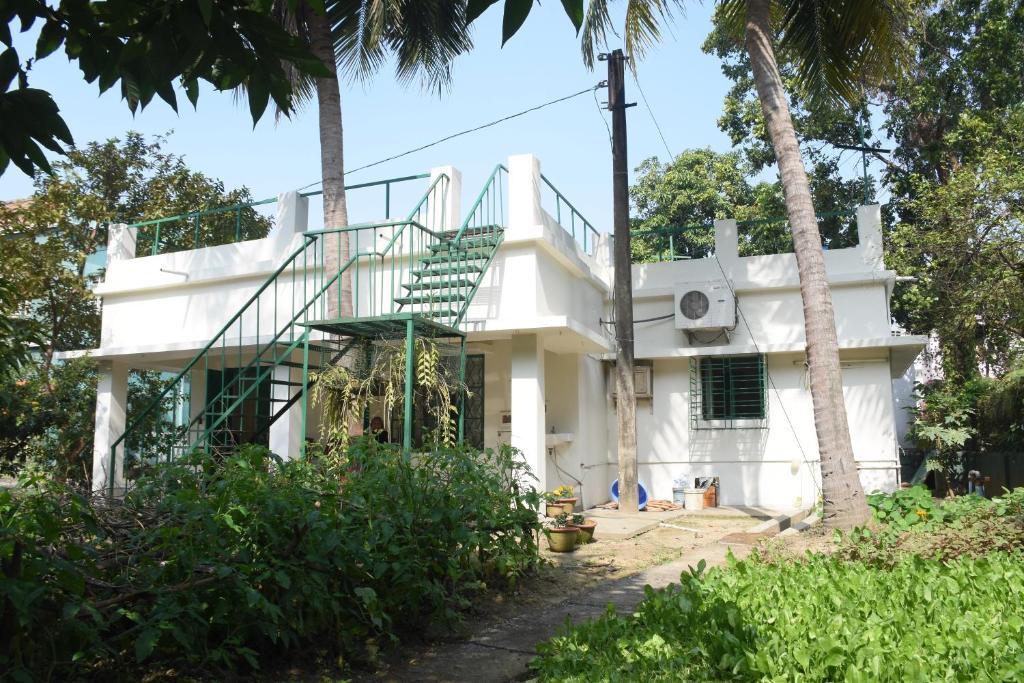 桑蒂尼盖登Bhitey Homestay SIMANTAPALLY / SHANTINIKETAN的白色的房子,前面有楼梯