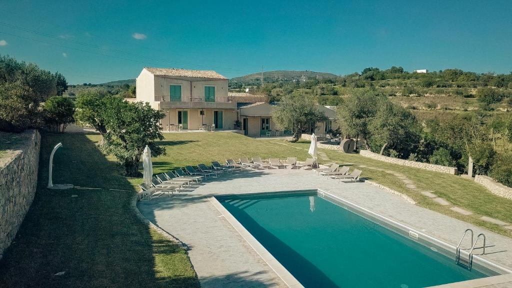 诺托Relais Terre di Romanello的房屋前有游泳池的房子