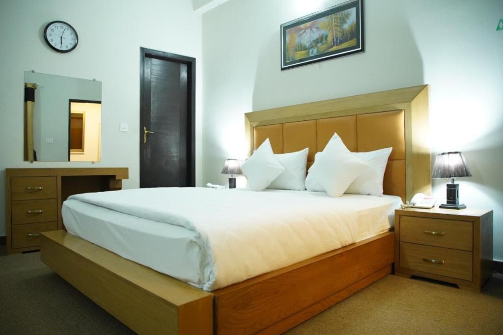伊斯兰堡Hotel Red Line的一间卧室配有一张大床,墙上挂着一个时钟