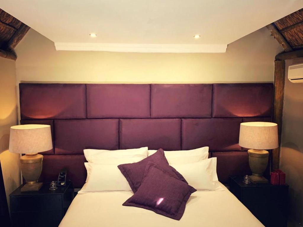 范德拜尔帕克Little Eden Guest Lodge的一间卧室配有一张大床和紫色床头板