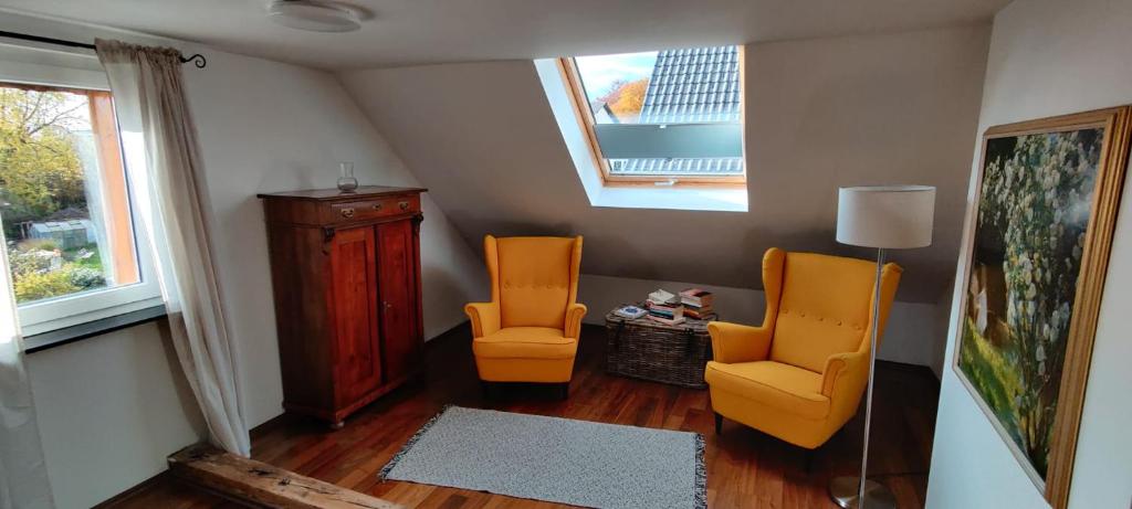比尔弗登Tinyloft的客厅配有两把橙色椅子和窗户