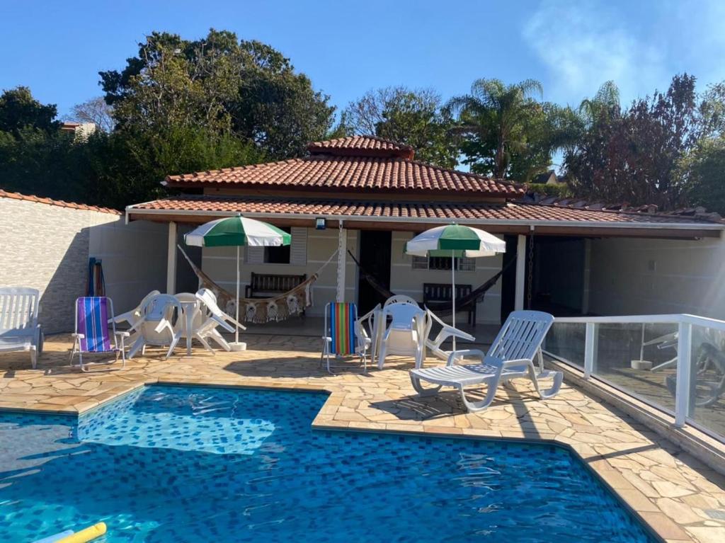 塞拉内格拉RANCHO KWILL的房屋旁的游泳池配有椅子和遮阳伞