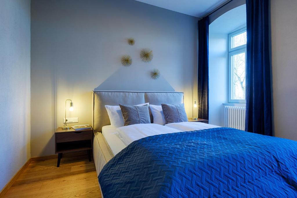 维尔茨堡Grimm's Schlossapartments Würzburg - by homekeepers的蓝色卧室配有一张带蓝色毯子的大床