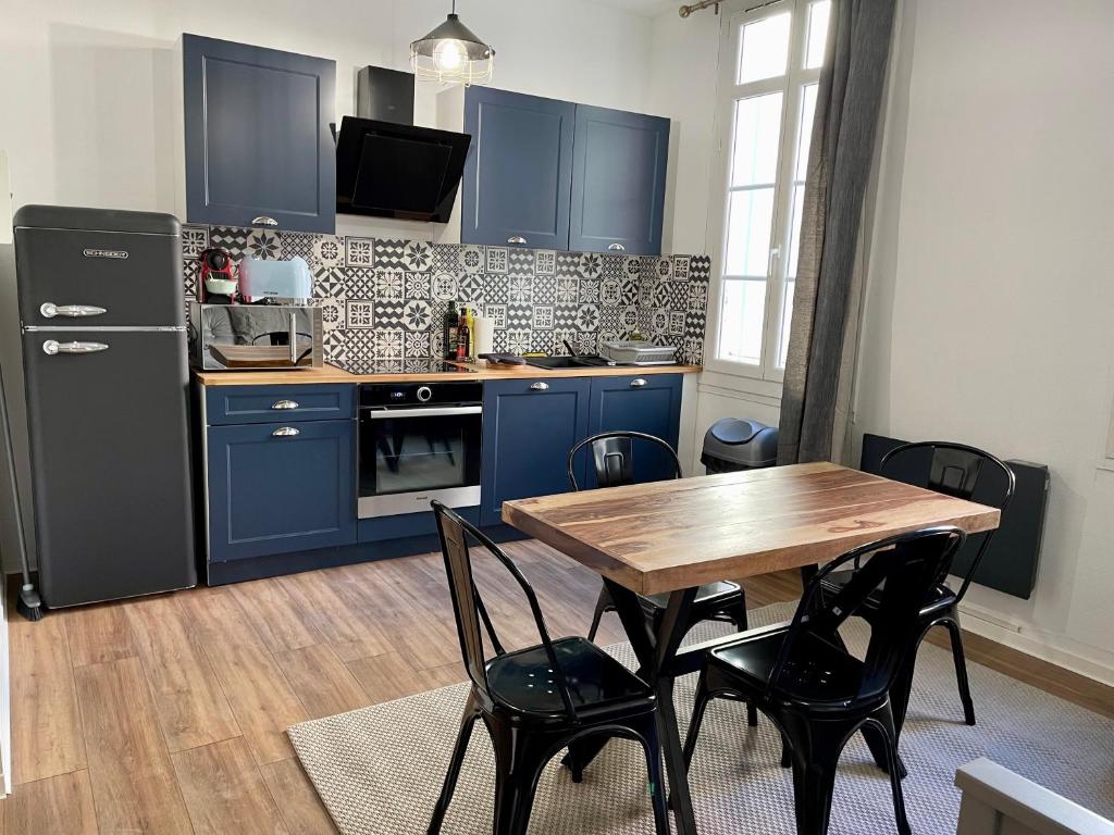 佩皮尼昂République - Dauder de Selva的厨房配有蓝色橱柜和一张带椅子的木桌