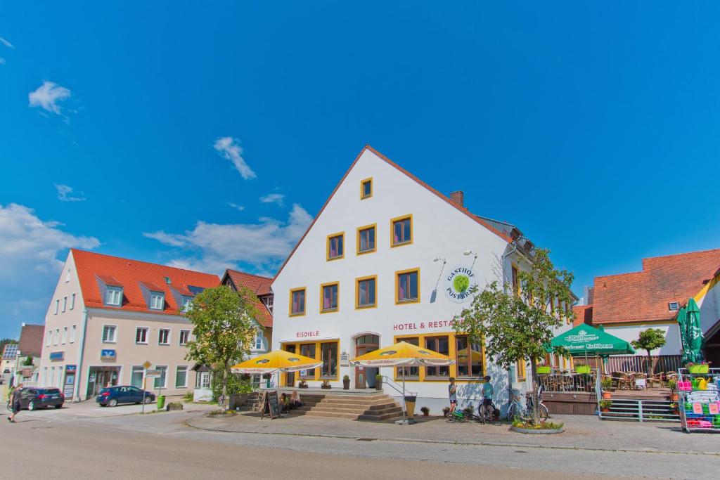 SiegenburgGasthof Postbräu的一座带遮阳伞的白色大建筑