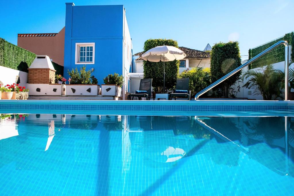 加拉奇科La casa de mi abuela的一个带蓝色房子和遮阳伞的游泳池