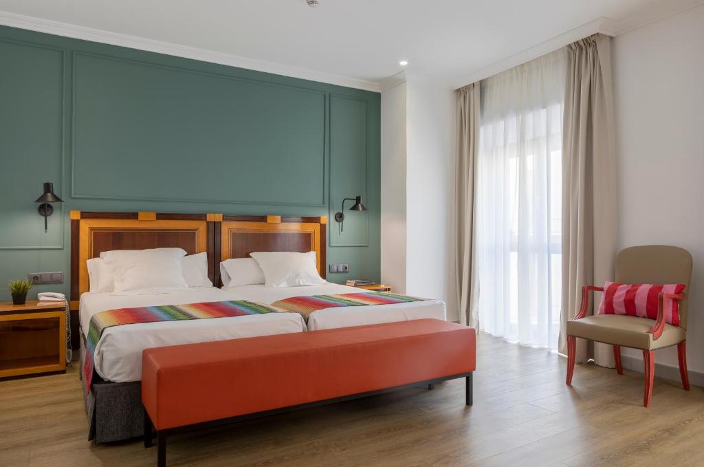 马拉加邓卡罗酒店的一间卧室配有一张大床和一把椅子