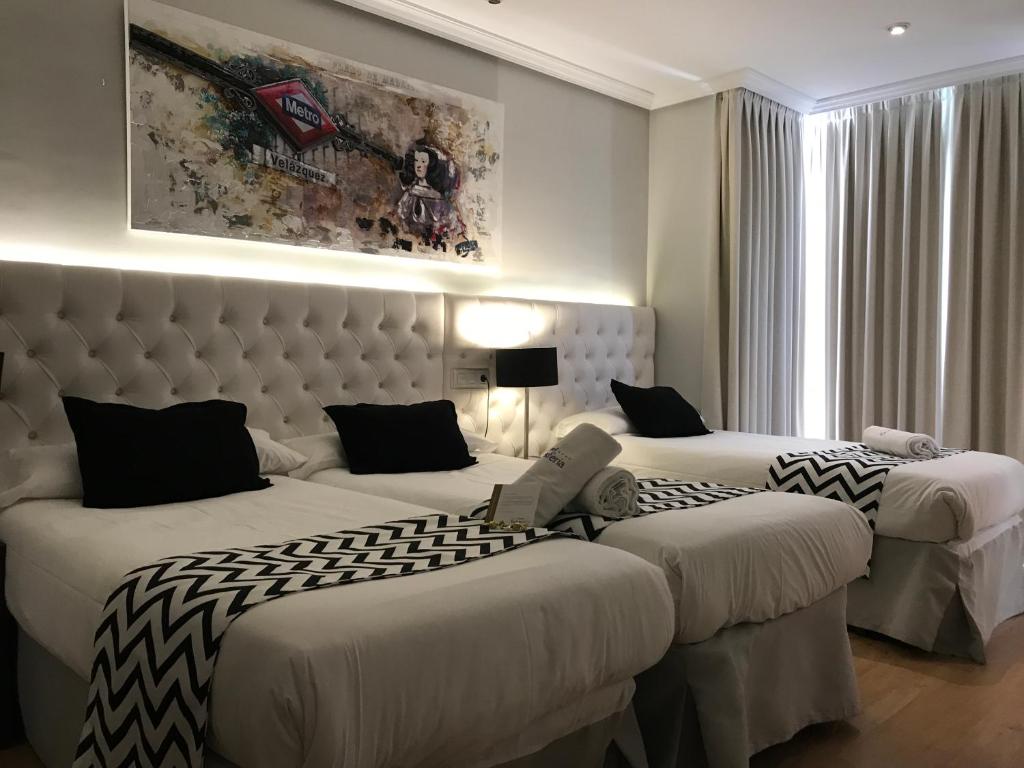 马德里Hotel Suites Feria de Madrid的酒店客房设有两张床和大窗户。