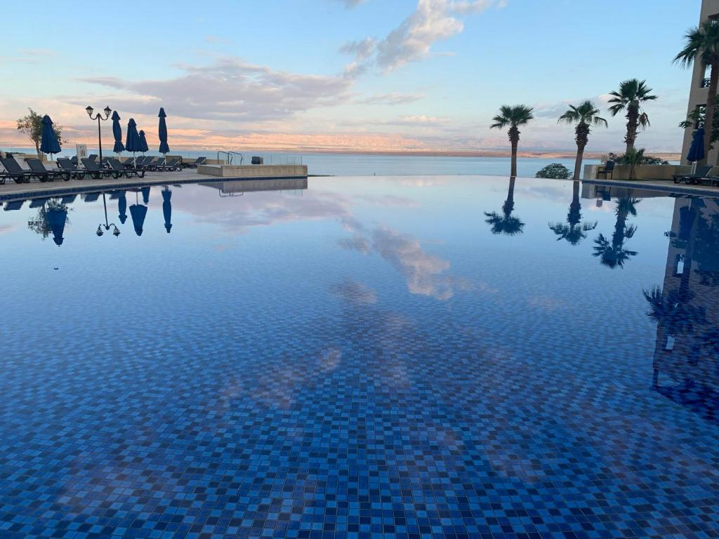 索瓦马Samarah Dead Sea Resort Studio-CP6 Traveler Award 2023 Winner的一座棕榈树和海洋的大型游泳池