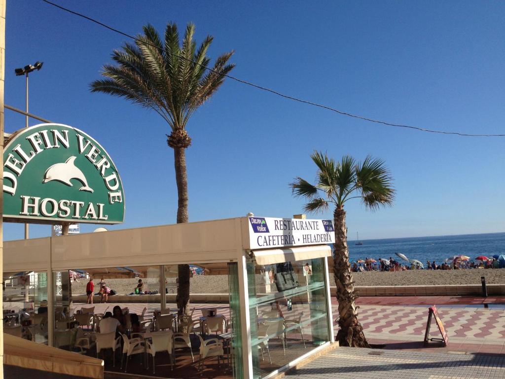 阿尔么丽亚Hostal Delfin Verde的棕榈树和海滩酒店标志