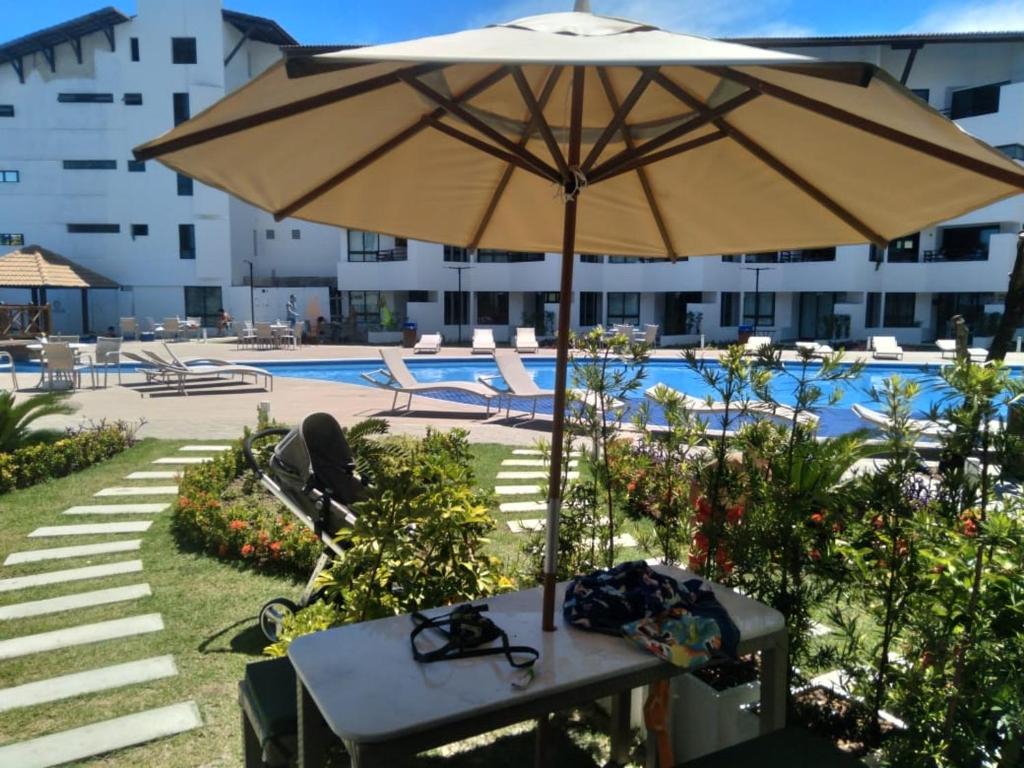 塔曼达雷Mauí beach resort的游泳池前带遮阳伞的桌子