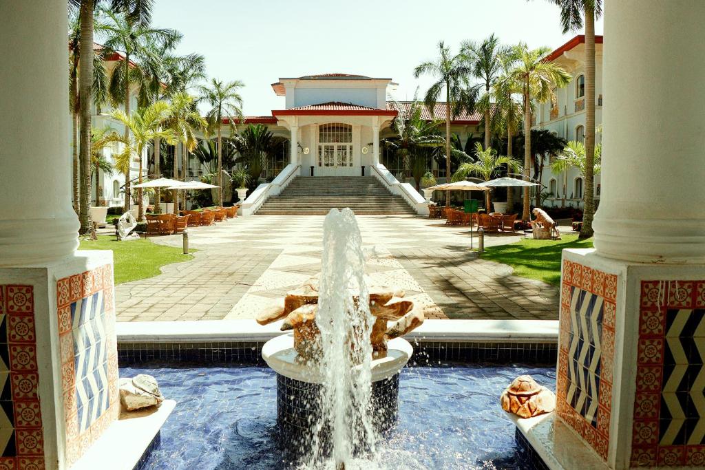 比亚埃尔莫萨Quinta Edén Villahermosa的棕榈树建筑前的喷泉