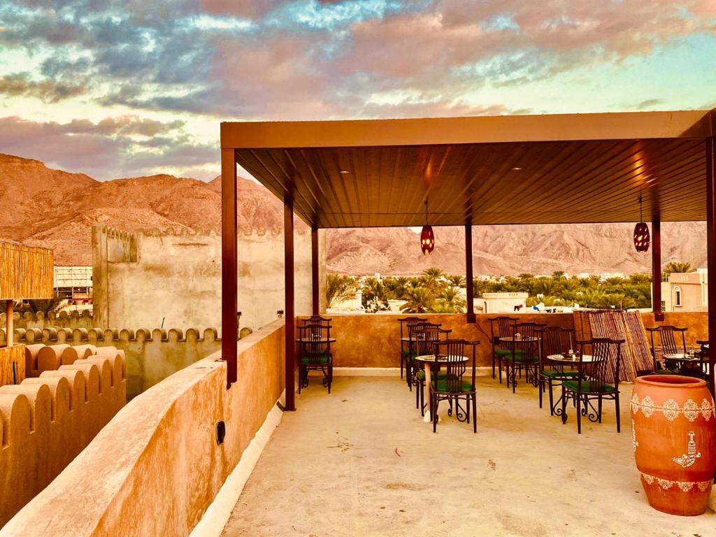 尼兹瓦Jawharat Alaqar Inn نزل جوهرة العقر的庭院配有桌椅,享有沙漠美景