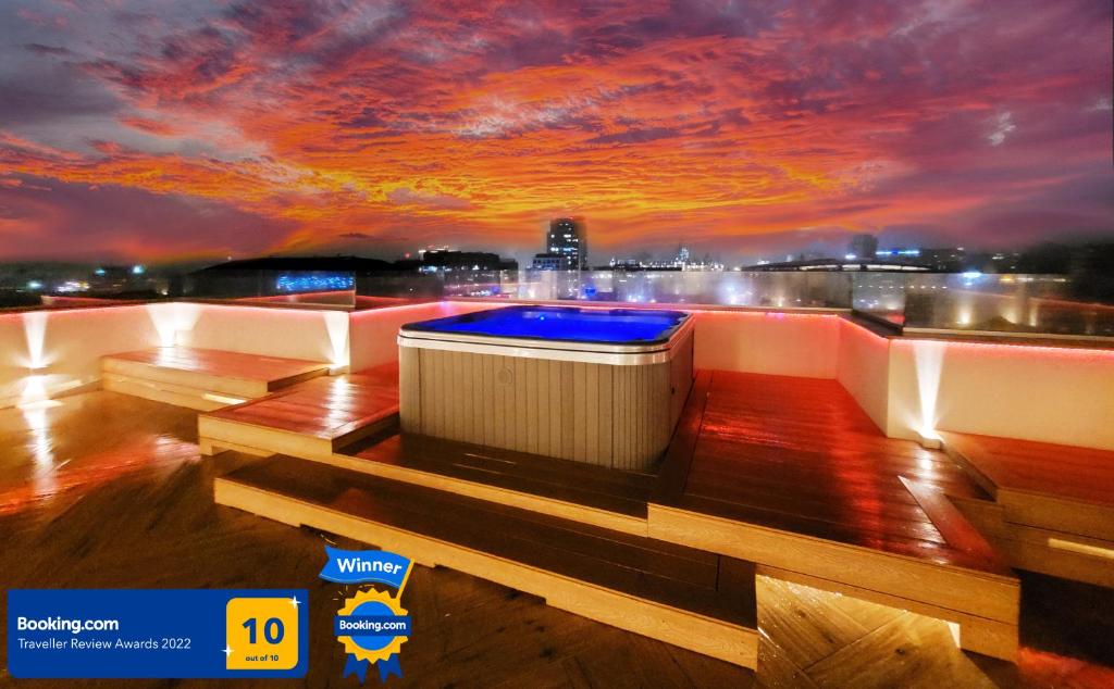 雅西Terrace Suites Iasi的一座享有日落美景的建筑屋顶上的热水浴池