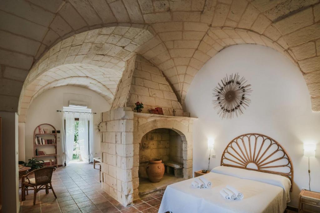 博尔加涅Agriturismo Masseria del Bosco Makyva的一间卧室设有石制壁炉和一张床