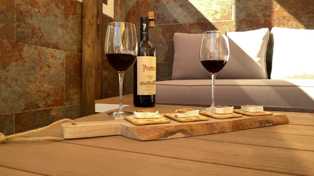 伊兹奎尔多Casa Carmen的一张木桌,上面放有两杯葡萄酒和奶酪