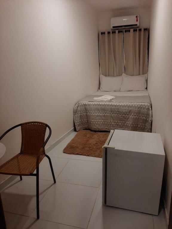 萨尔瓦多Aconchego de Itapuã的小房间设有一张床和一把椅子