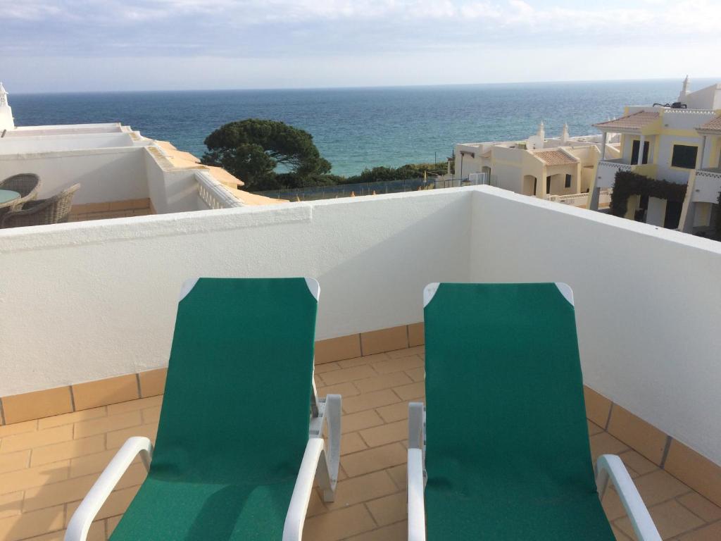 贝纳吉Seaview Benagil Villa 15的阳台设有两把绿色椅子,俯瞰着大海