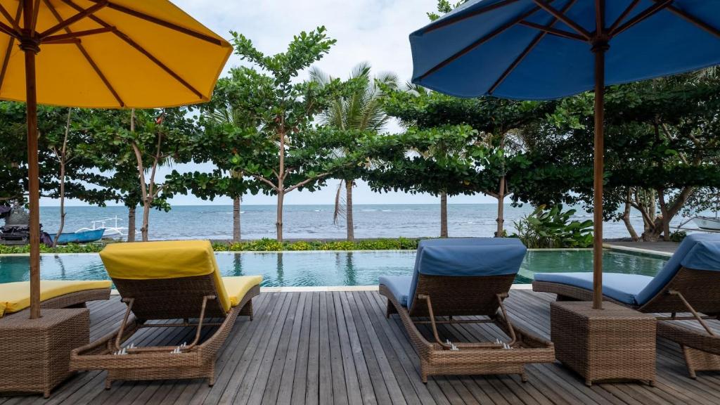罗威那The Grand Villandra Resort的游泳池旁的甲板上配有椅子和遮阳伞
