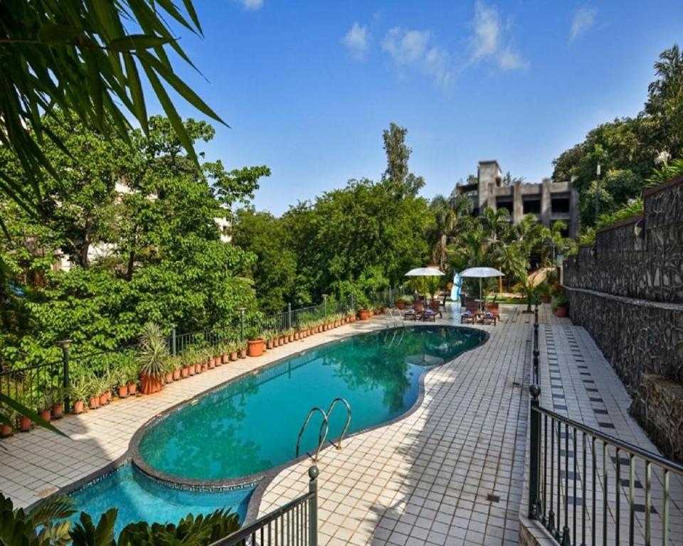 罗纳瓦拉Meritas Crystal Resort的树木繁茂的度假胜地的游泳池