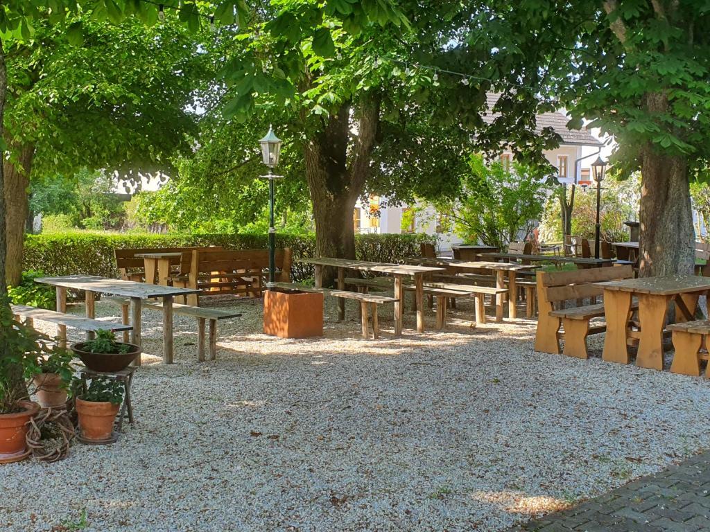 AdlkofenLandgasthof Geltinger的一组野餐桌和树下的长椅
