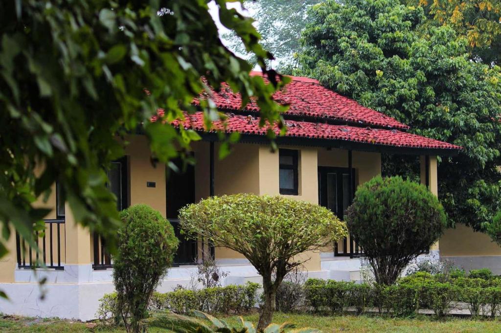 BardiyāBardia Forest Resort的一座房子前面有树木的红色屋顶