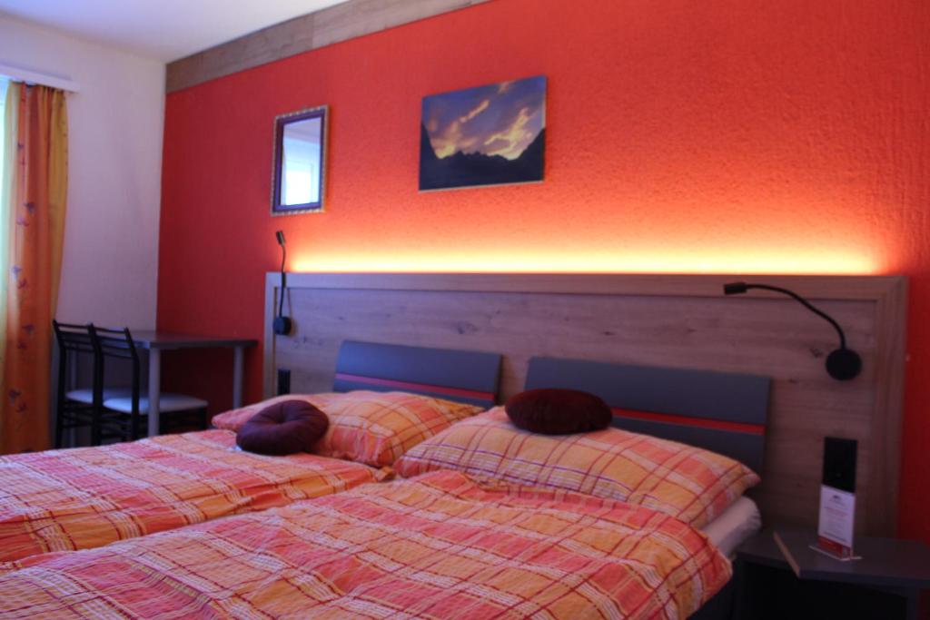伊森塔尔乌里罗斯托酒店的卧室设有两张床铺和红色的墙壁