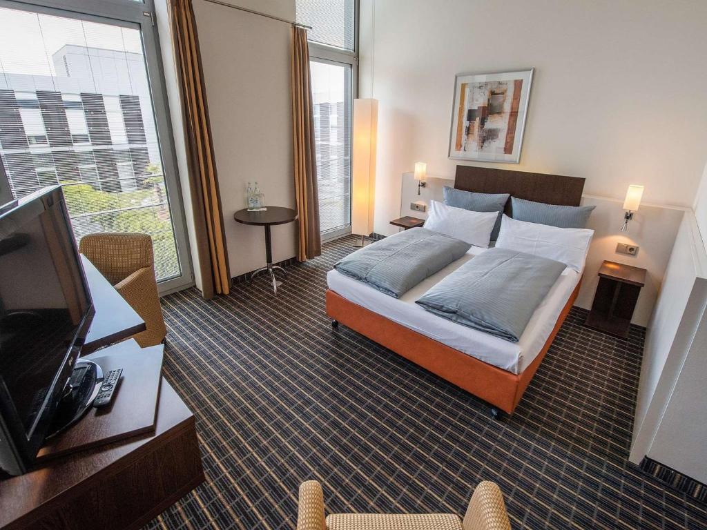 因戈尔施塔特Livenwork Hotel & CoWorking GVZ Ingolstadt的配有一张床和一台平面电视的酒店客房