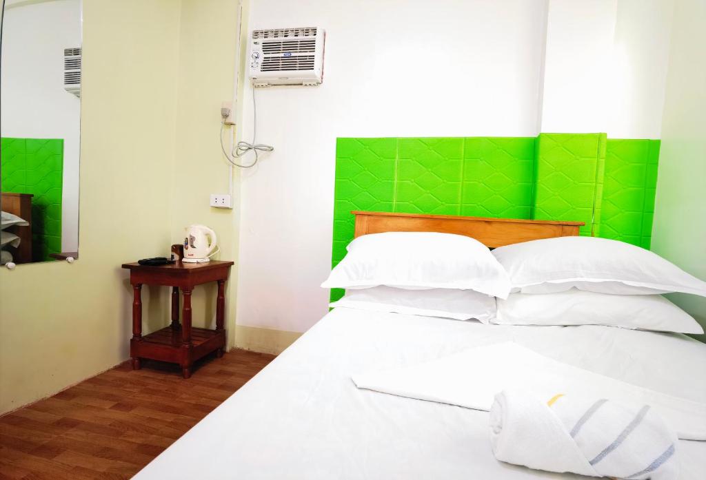 土格加劳RedDoorz D128 Lodge Cagayan Valley的一间卧室配有一张白色床和绿色床头板