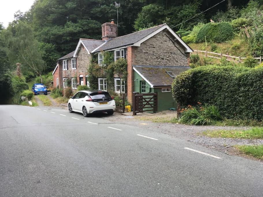 拉尼德洛伊斯200 year old Gardener's cottage, Mid Wales的停在房子前面的白色汽车