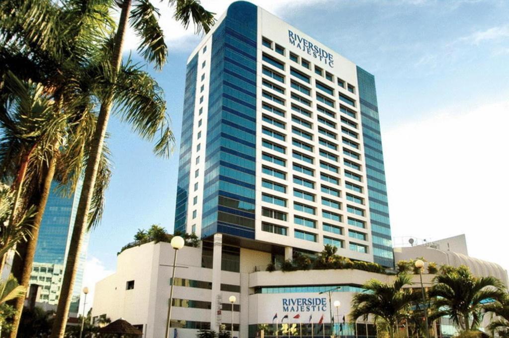 古晋Puteri Wing - Riverside Majestic Hotel的一座高大的建筑,前面有棕榈树