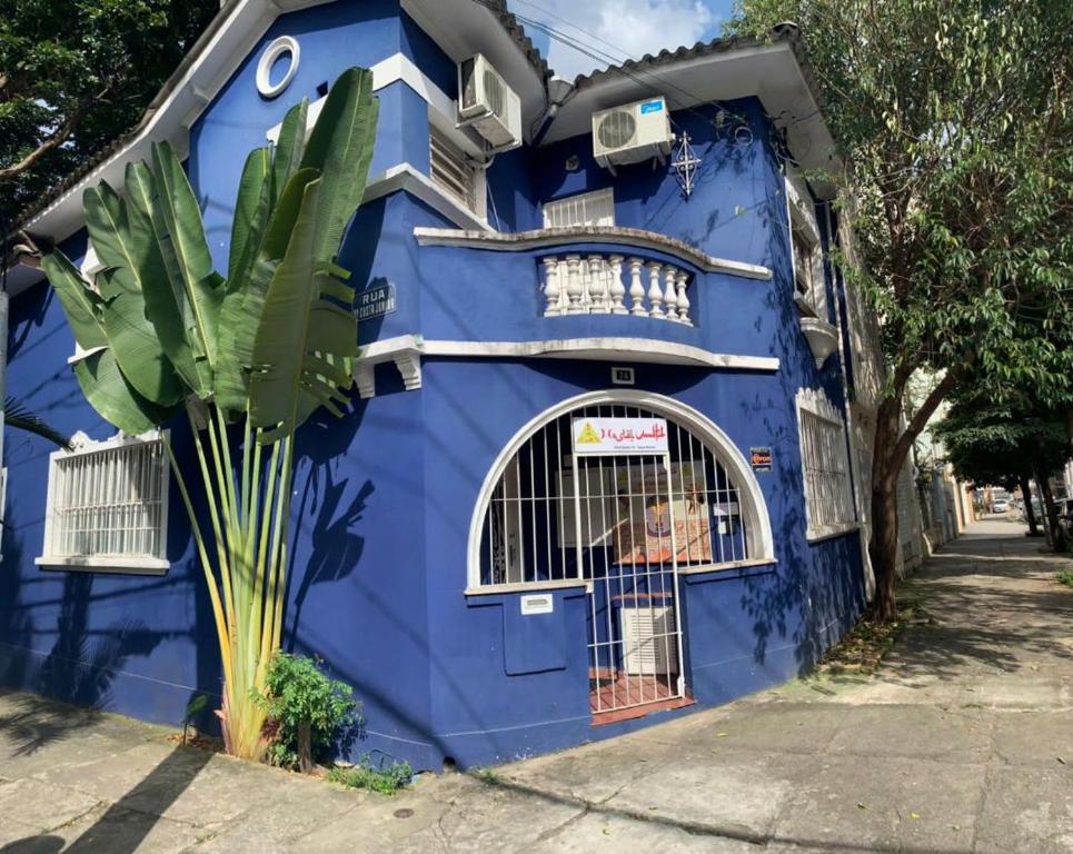 圣保罗Hostel Maktub的前面有棕榈树的蓝色房子