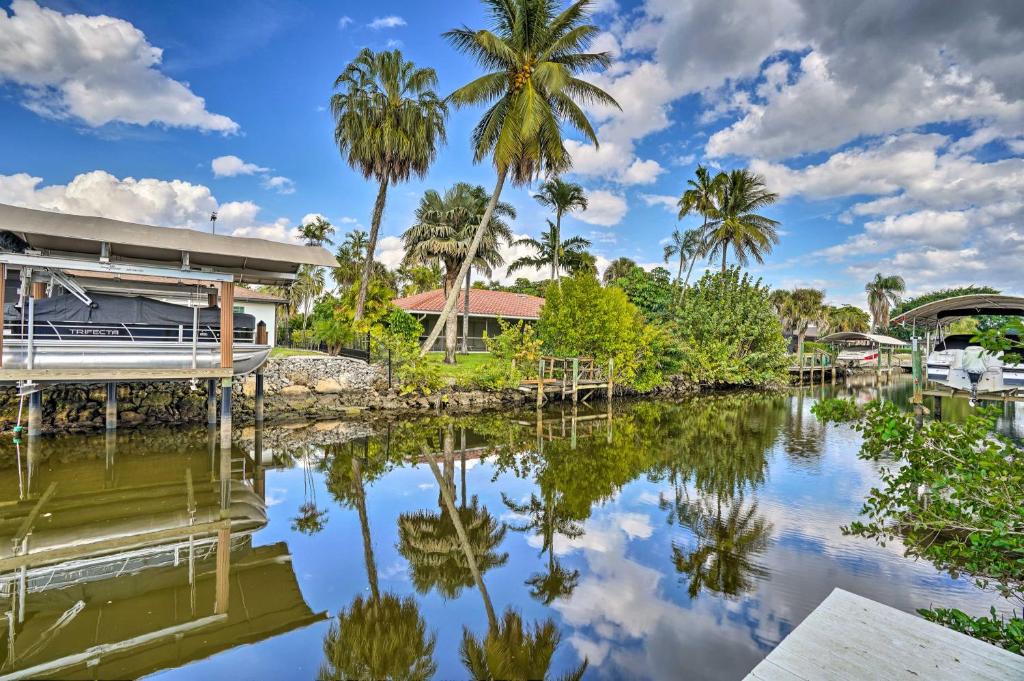 那不勒斯Sunny Naples Home with Pool, Direct Gulf Access的棕榈树水边的房子