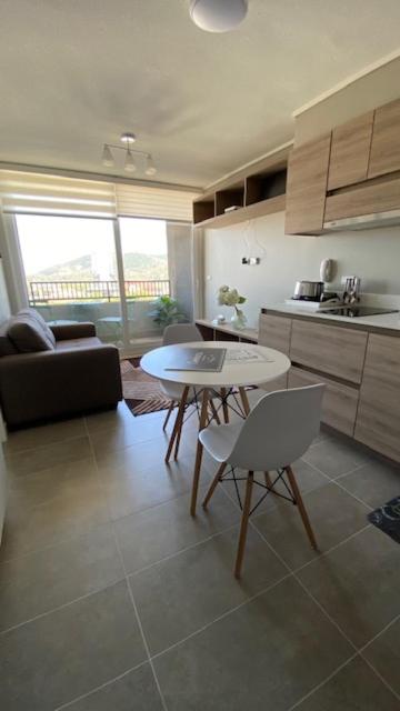 特木科Apart Center Temuco的厨房以及带桌椅的起居室。