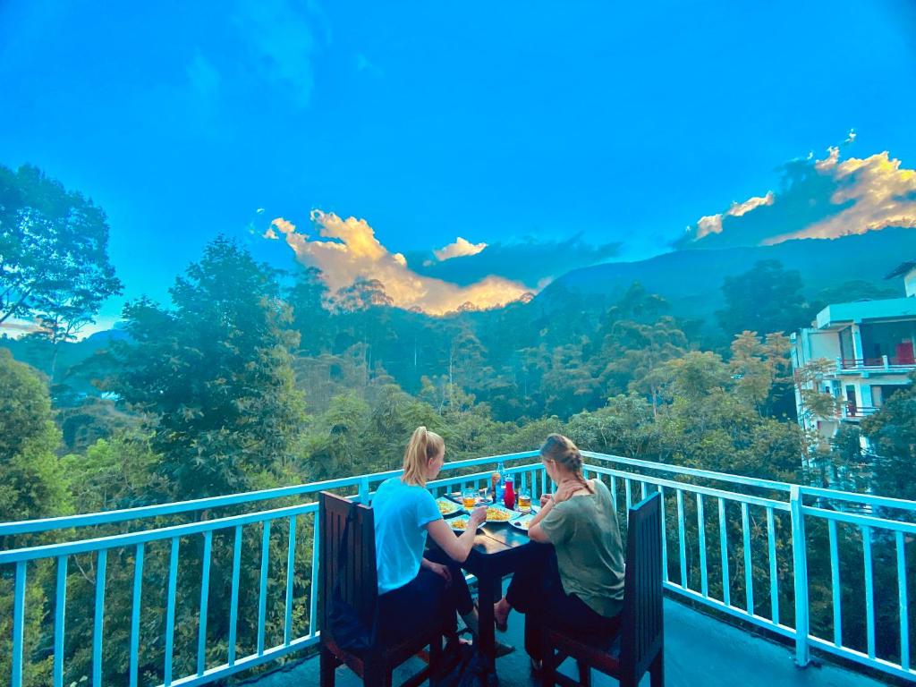 纳拉坦尼亚Adams Peak Inn的坐在阳台上桌子上的男人和女人