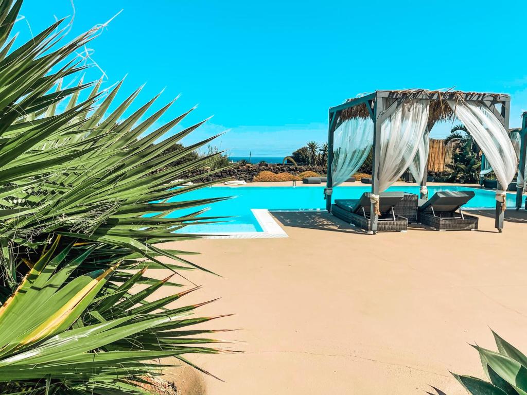 潘泰莱里亚I Dammusini di Pantelleria的海滩上带凉亭和椅子的游泳池