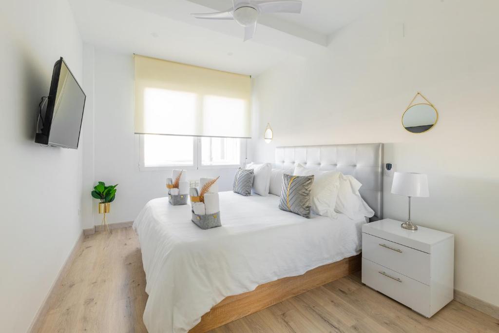 马德里SWEET DREAMS APARTMENT NEAR PUERTA DEL SOL的白色的卧室配有白色的床和电视。