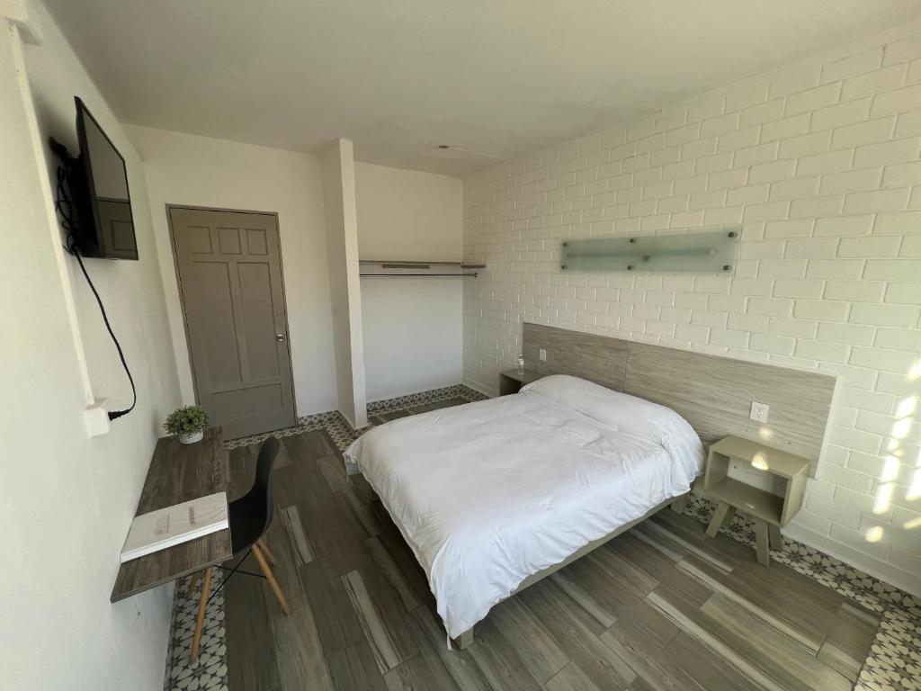 圣路易斯波托西Hotel Insurgentes的卧室配有白色的床和电视。