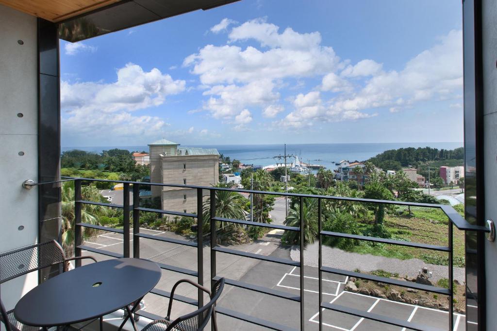 西归浦市福美来酒店的阳台配有桌椅,享有海景。