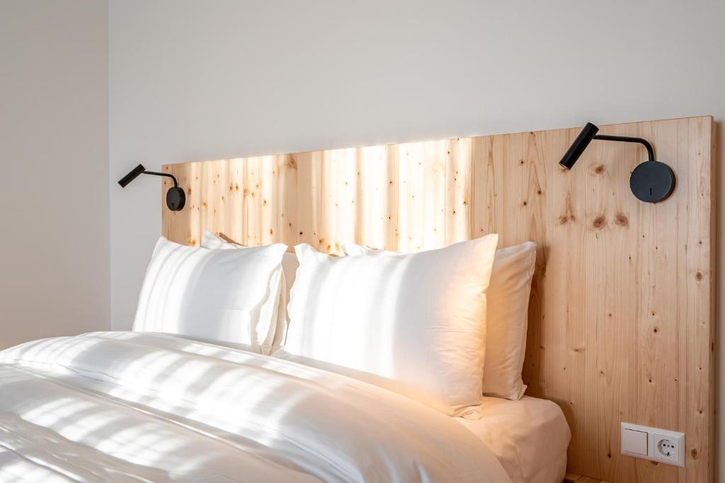 弗莱堡Arbio Hotel Freiburg的一张带白色枕头和木制床头板的床