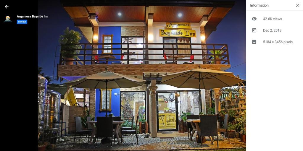科隆Argamosa Bayside Inn的大楼前的餐厅,配有桌子和遮阳伞