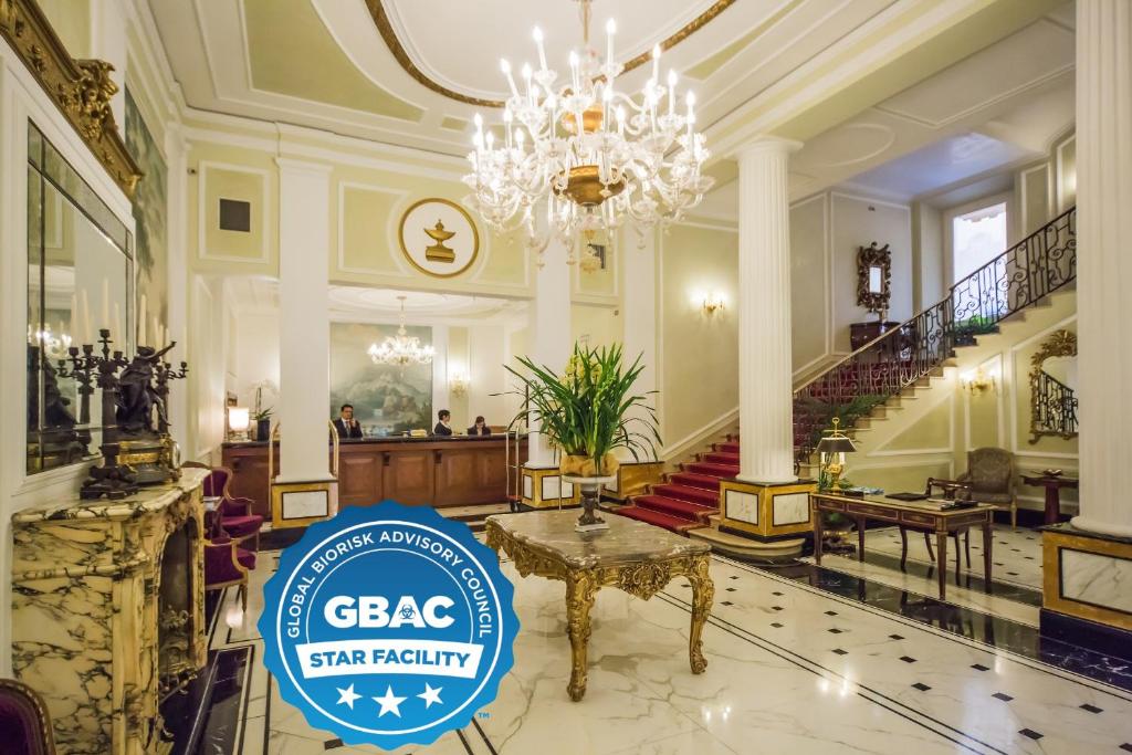 博洛尼亚吉亚巴利奥尼大酒店的大堂设有吊灯和标牌,上面标有Gaba星的设施