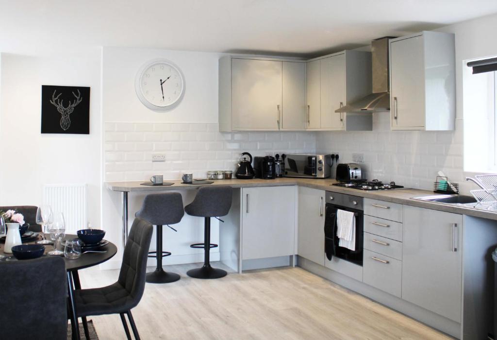 阿宾登Abingdon - Private Flat with Parking 09的厨房配有白色橱柜、桌子和时钟